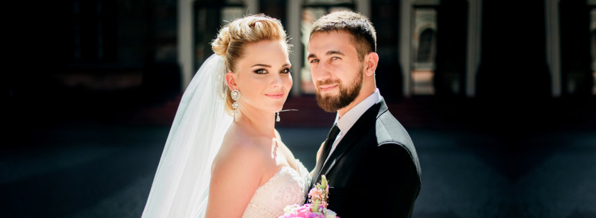 groom holds bride's waist tender while they pose on the pavement backyard